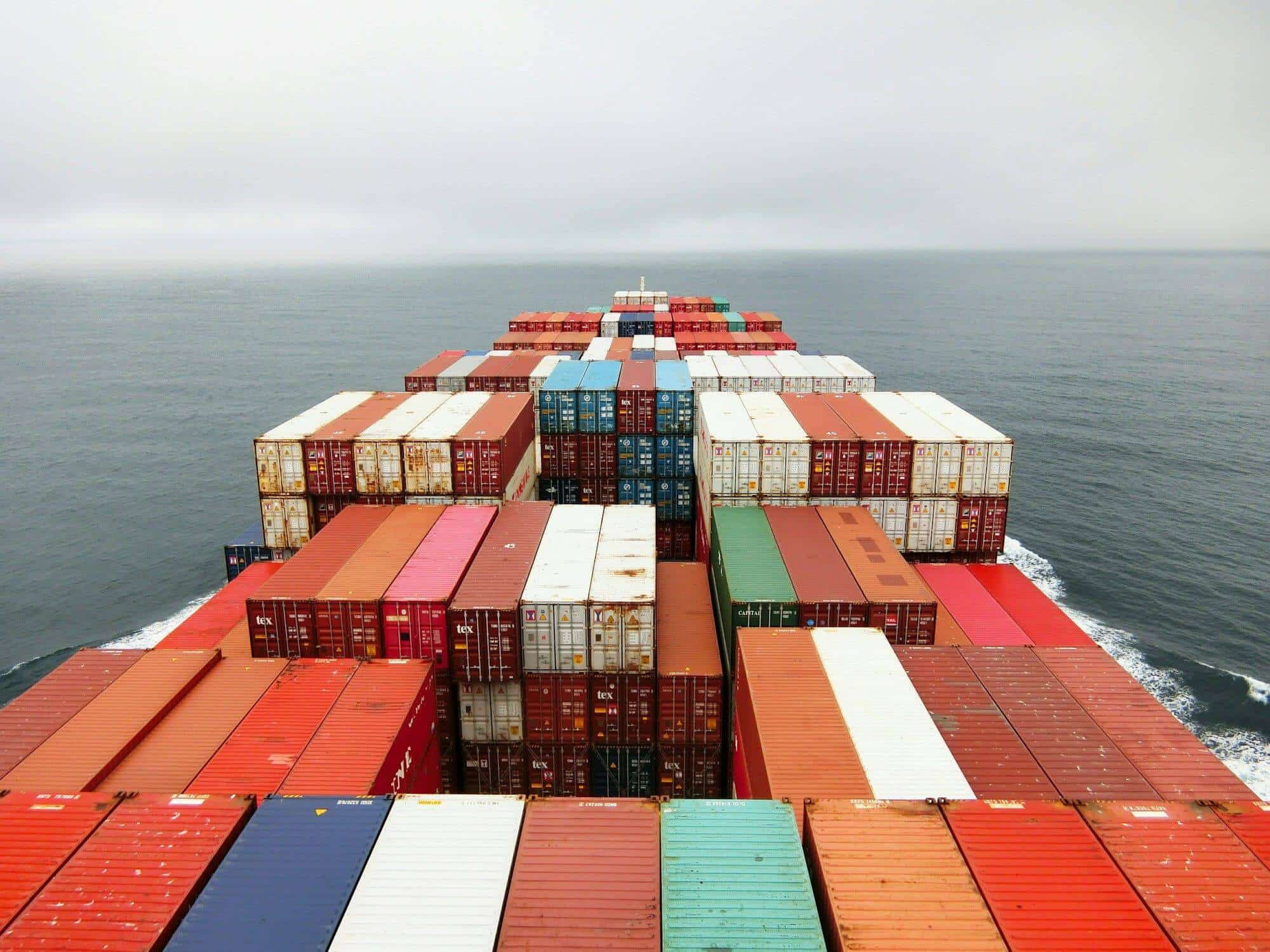 View over stacked containers from the bridge of a ship heading out to sea