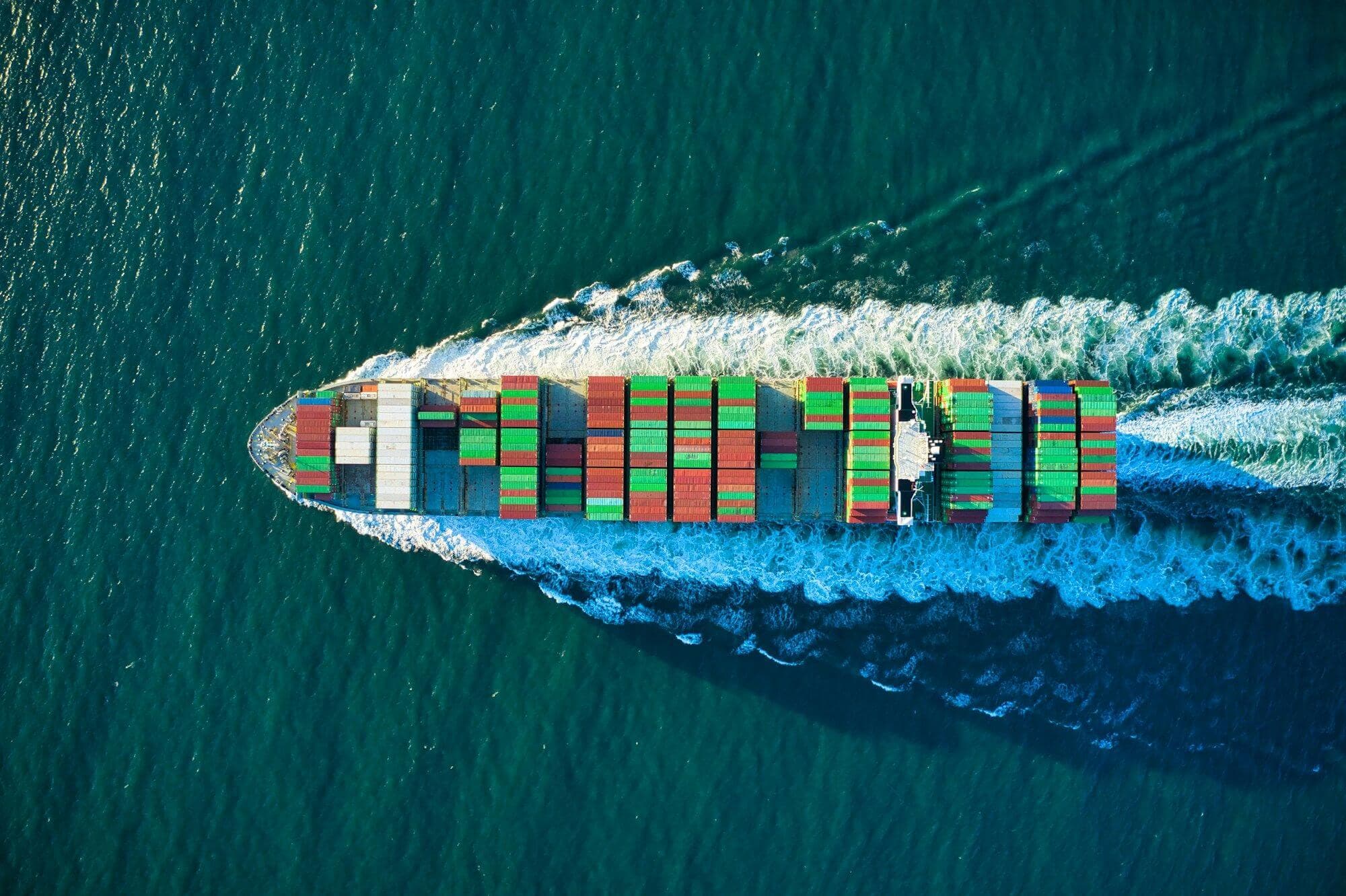 Aerial view of a container ship cutting through deep blue water
