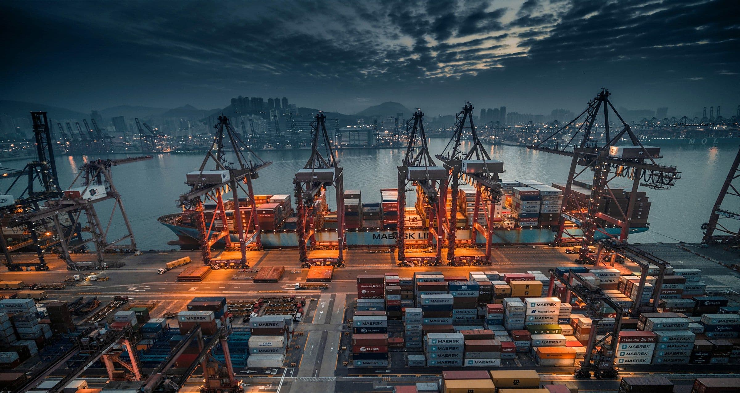 Container port with gantry cranes lit up at dusk