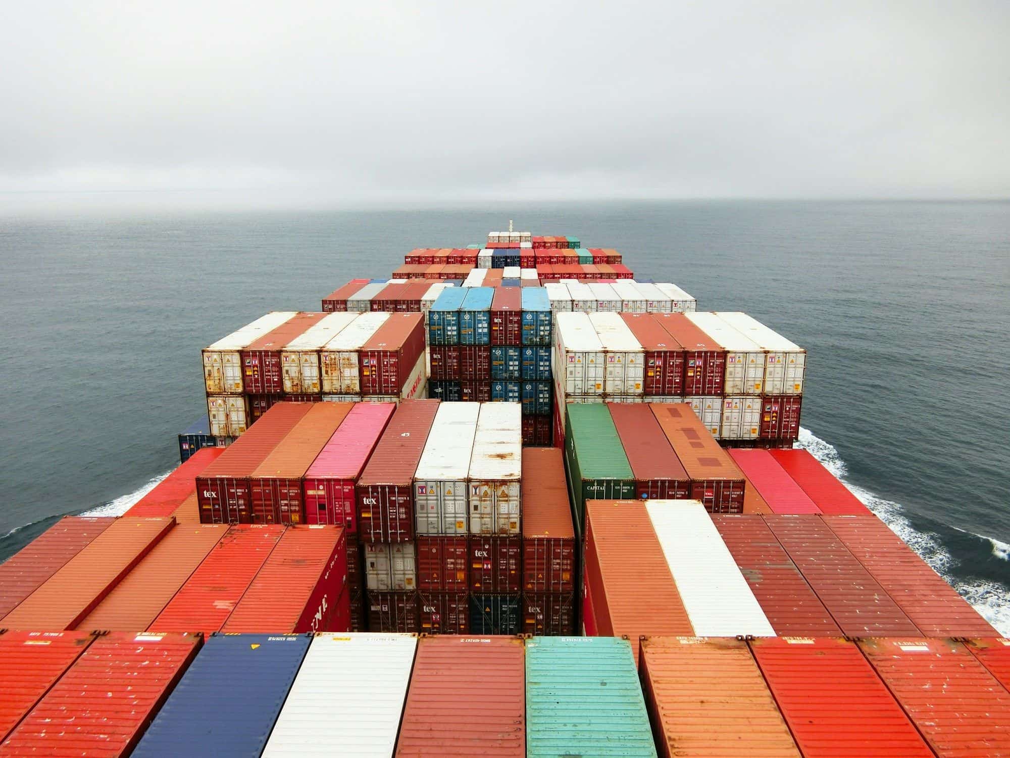 View over stacked containers from the bridge of a ship heading out to sea